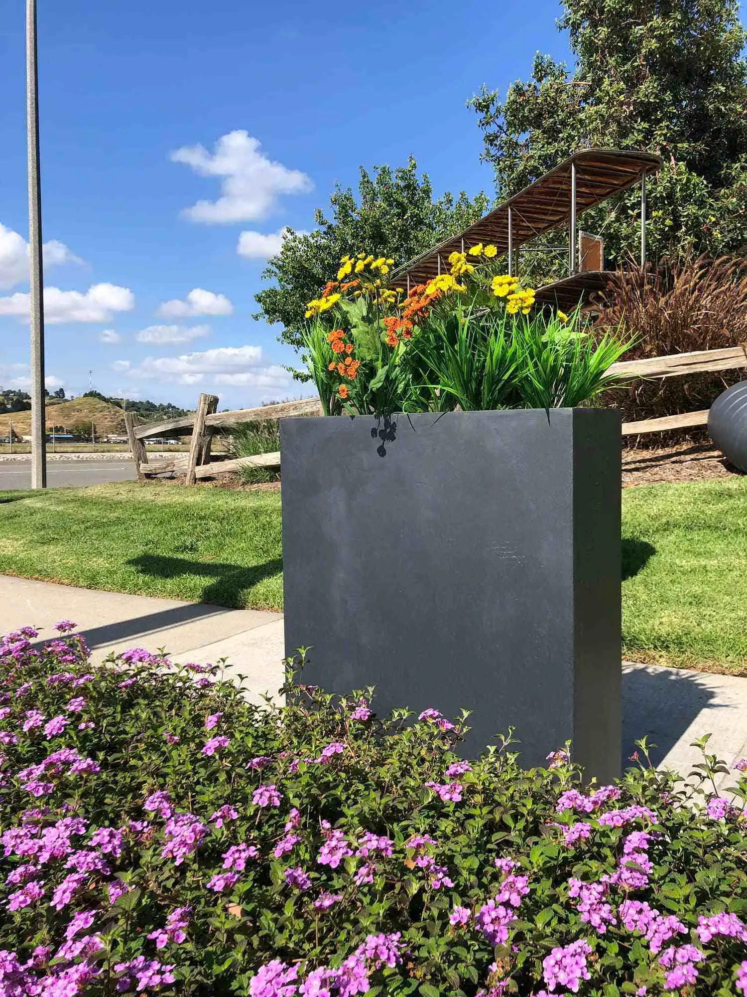 Black GRC rectangular planter box used as a roadside divider in public spaces